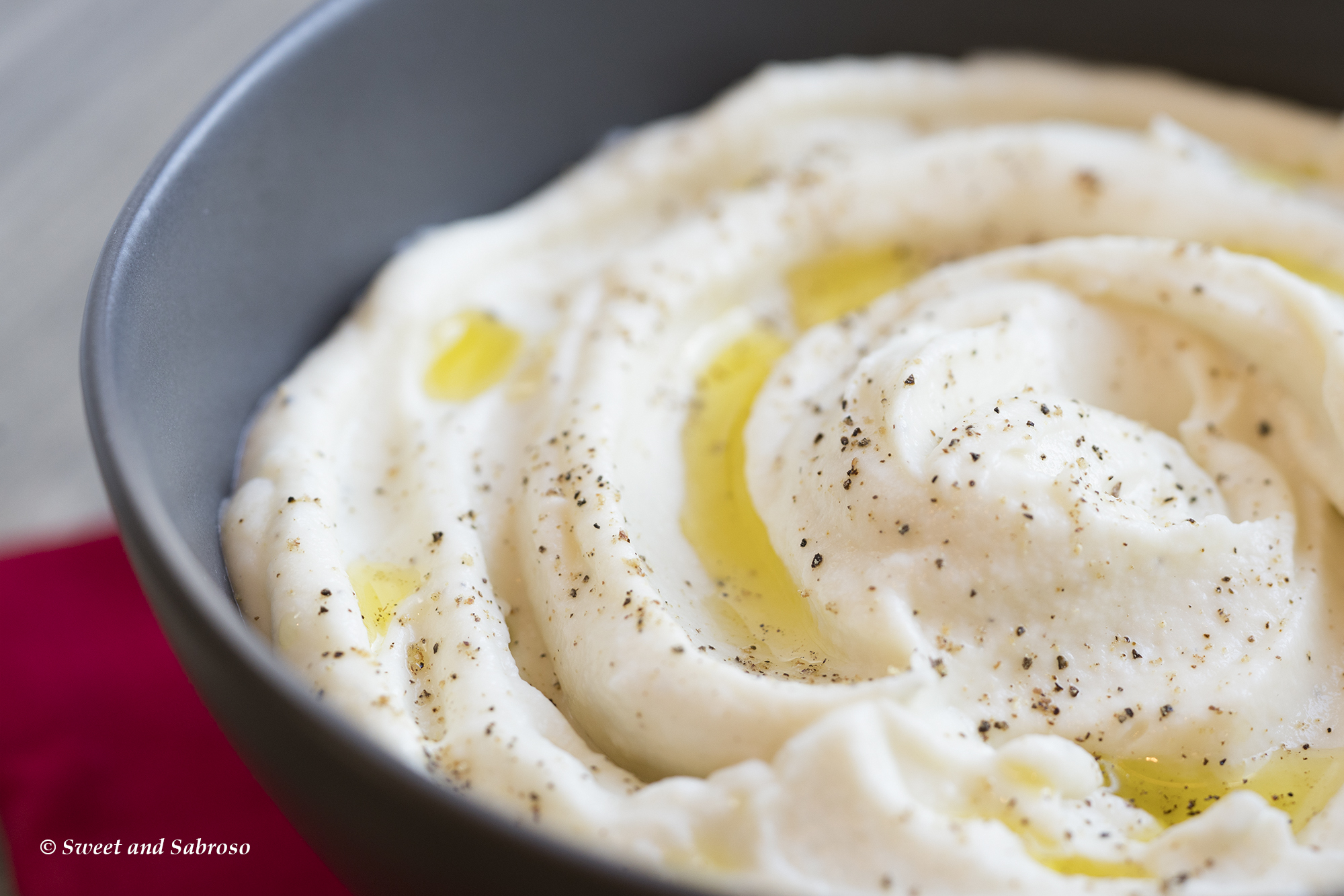 Creamy Cauliflower Purée with Manchego Cheese and Olive Oil: pictured in a pewter bowl, seasoned with black pepper and drizzled with olive oil