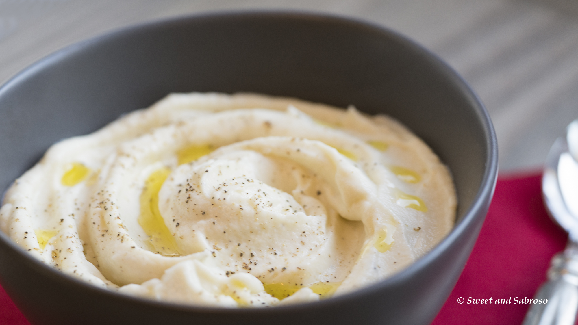 Creamy Cauliflower Purée with Manchego Cheese and Olive Oil: pictured in a pewter bowl, seasoned with black pepper and drizzled with olive oil