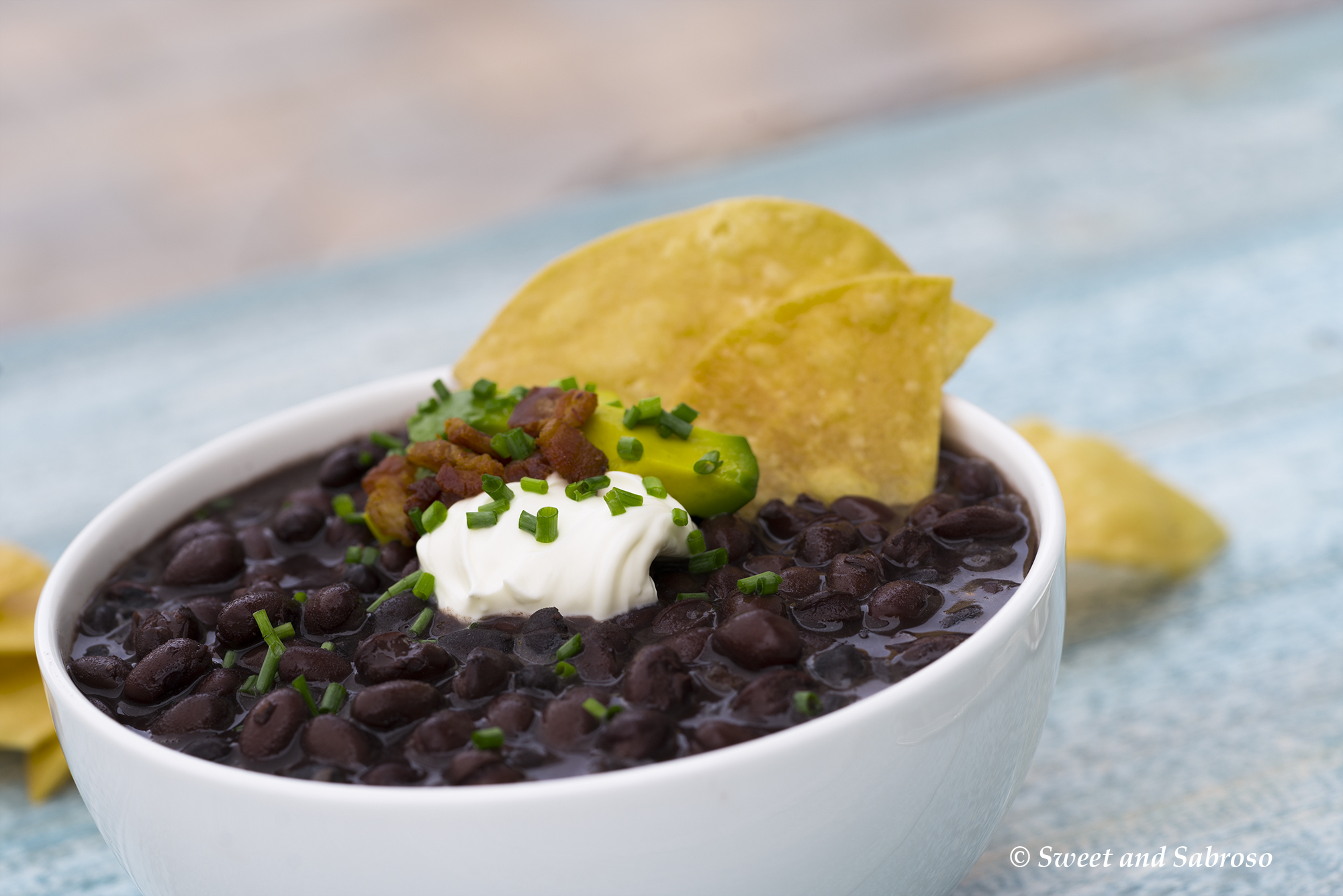Cuban Black Beans with Bacon Garnished with Avocado, Crème Frâiche and Chives