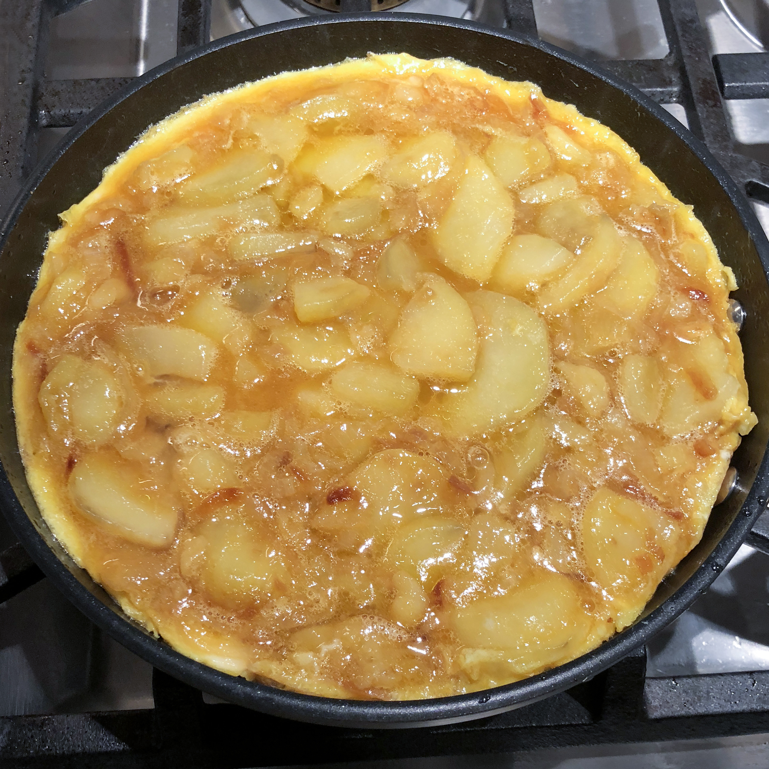 Tortilla Española (Spanish Omelet) cooking in nonstick pan prior to flipping it over.